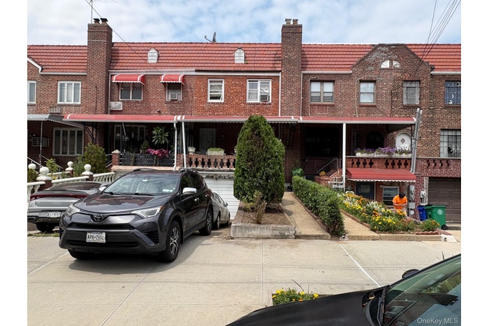 View of front of house featuring brick siding, a chimney, and mansard roof