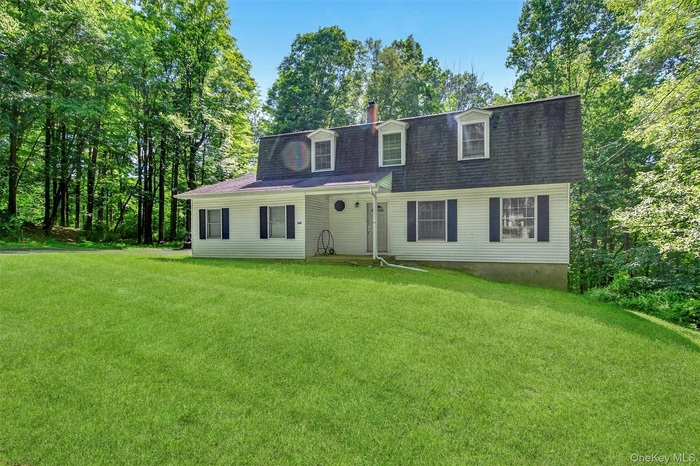View of front of home featuring a front yard, a shingled roof, and a chimney