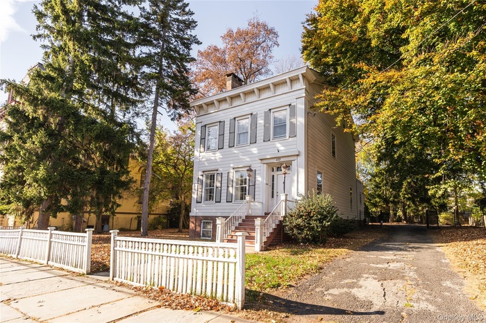 View of front of home featuring a fenced front yard, a chimney, and driveway