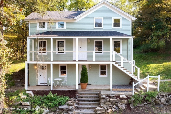 View of front of property with covered porch, stairway, and a shingled roof
