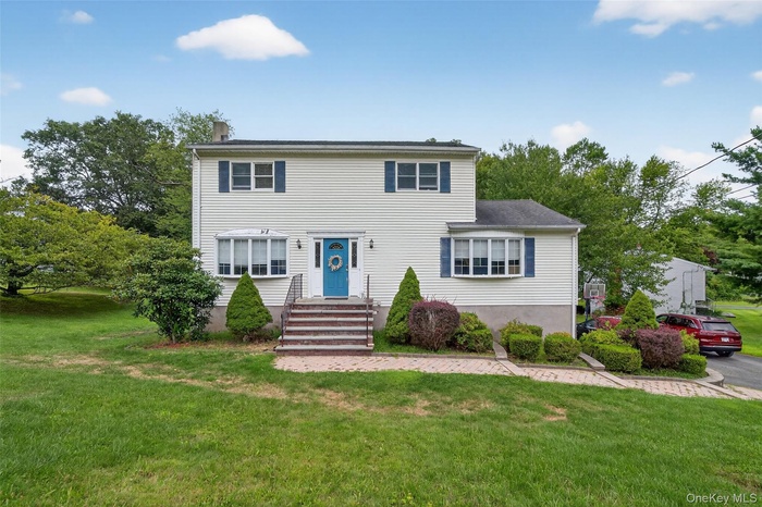Colonial-style house with a front lawn and a chimney