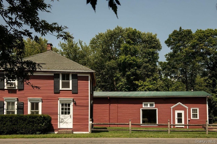 Rear view of property featuring a chimney, a lawn, and a metal roof