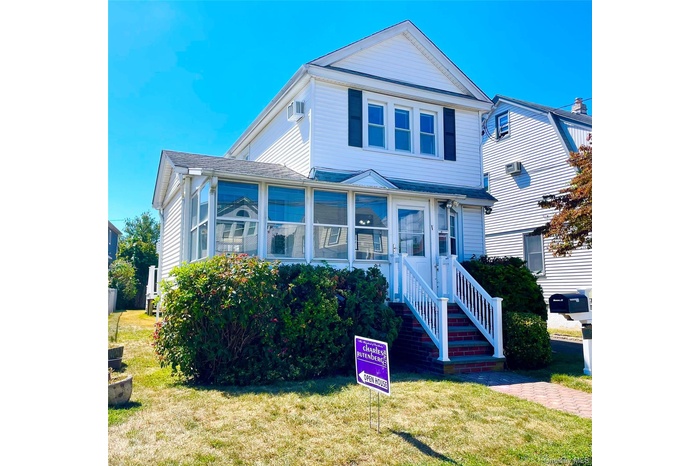 View of front of home with a sunroom and a front lawn