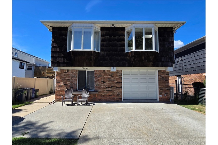View of front of property featuring mansard roof, brick siding, a garage, and driveway