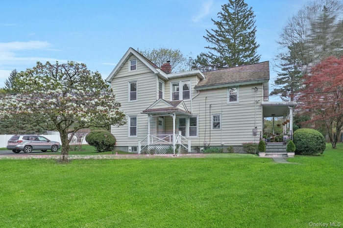 View of front of property with a chimney, a front lawn, and a porch