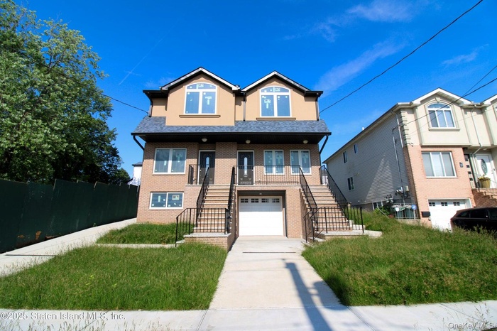 View of front of house featuring stairs, concrete driveway, an attached garage, brick siding, and stucco siding