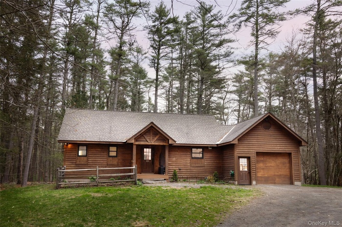 View of front of home with roof with shingles, an attached garage, and a front lawn
