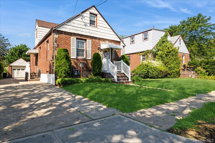 Bungalow-style house with an outdoor structure, brick siding, a detached garage, a front lawn, and driveway