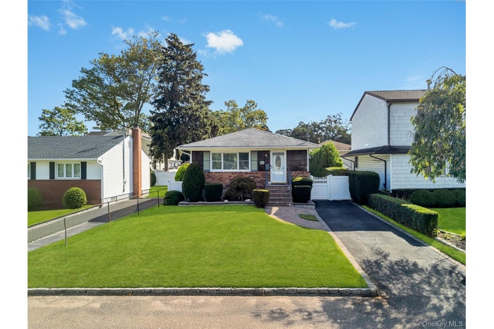 Bungalow-style house featuring brick siding, asphalt driveway, and a gate