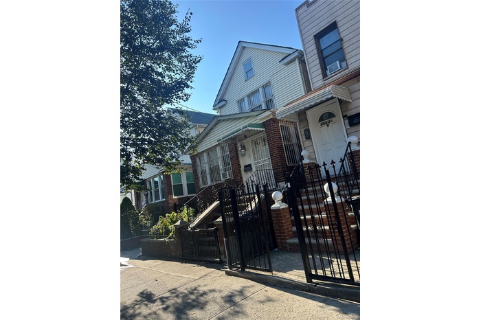 View of front of property featuring a gate, a fenced front yard, and brick siding