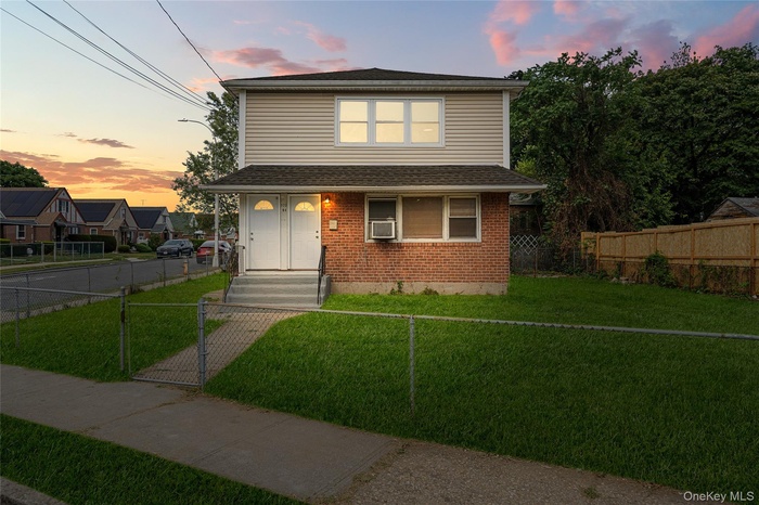 View of front of home featuring brick siding, a fenced front yard, roof with shingles, a gate, and cooling unit