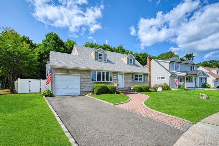 Cape cod-style house with a gate, driveway, a shingled roof, and an attached garage
