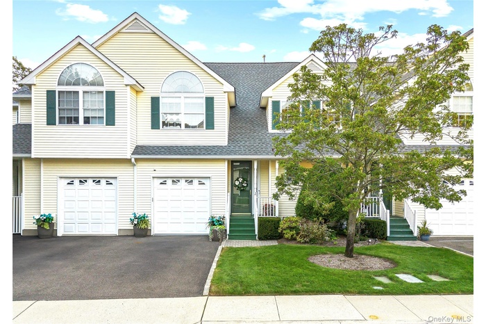 Traditional home with roof with shingles, driveway, a garage, and a front lawn