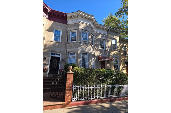 Italianate-style house with brick siding and a fenced front yard