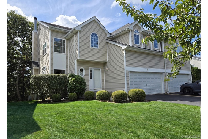Traditional home with a garage, asphalt driveway, and a front lawn