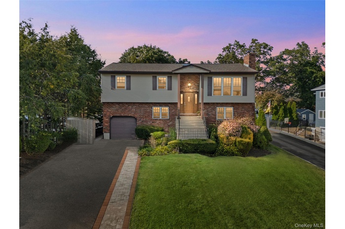 Hi-ranch with brick siding, a chimney, asphalt driveway, and an attached garage