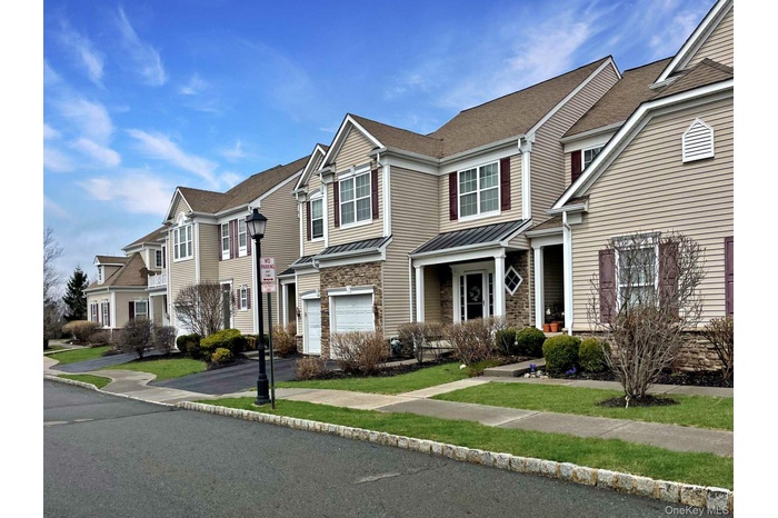 Traditional-style house featuring a residential view, an attached garage, a standing seam roof, a shingled roof, and driveway