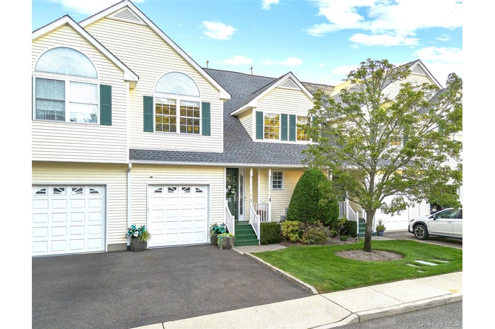Traditional home featuring roof with shingles, driveway, a front lawn, and an attached garage