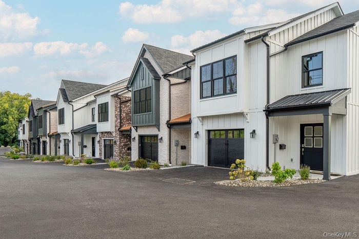 Modern farmhouse style home featuring a residential view, board and batten siding, a garage, and asphalt driveway