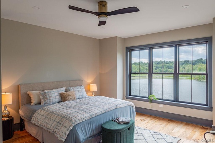 Bedroom with wood finished floors, a stunning water  view, and a ceiling fan