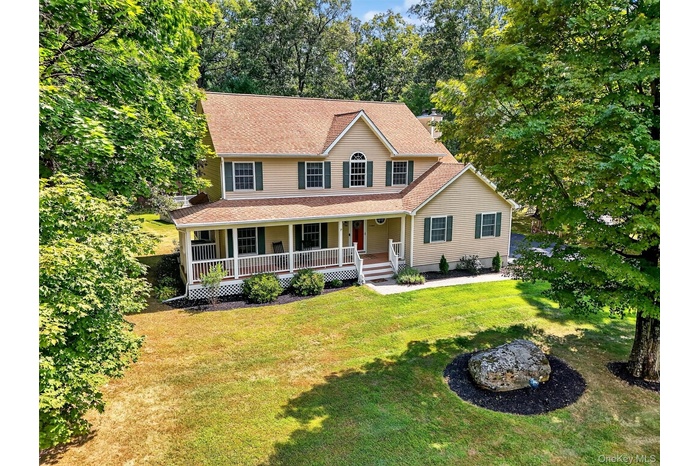 View of front of house featuring covered porch, roof with shingles, a front yard, and a chimney