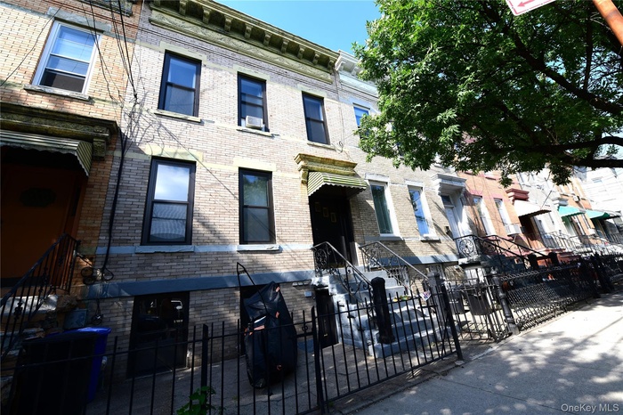 Italianate house featuring a fenced front yard, brick siding, and a gate