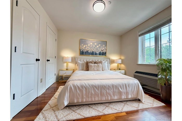 Bedroom with wood finished floors and an AC wall unit