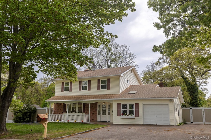 View of front facade featuring covered porch, a gate, driveway, a garage, and a chimney