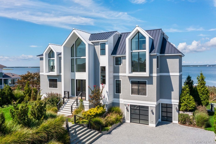 Contemporary house with a water view, driveway, a garage, and a metal roof