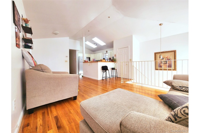 Living room featuring light wood-style floors, vaulted ceiling, and a skylight