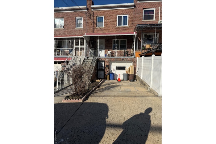 Rear view of property with brick siding, fence, stairs, cooling unit, and driveway