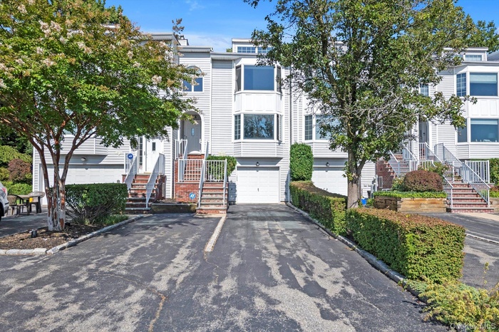 View of property featuring asphalt driveway, a garage, and stairs