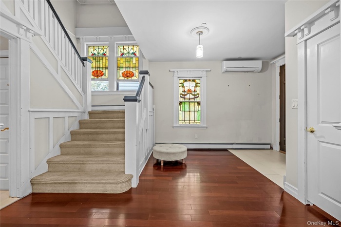 Stairs featuring hardwood / wood-style floors, an AC wall unit, and a baseboard heating unit