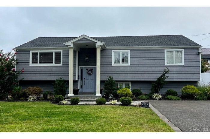 Bi-level home with a front lawn and a shingled roof