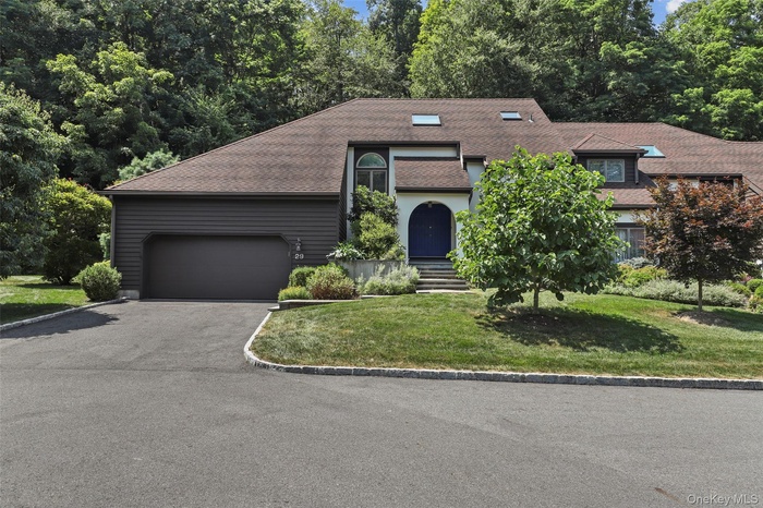 View of front facade with driveway, a front yard, roof with shingles, and an attached garage