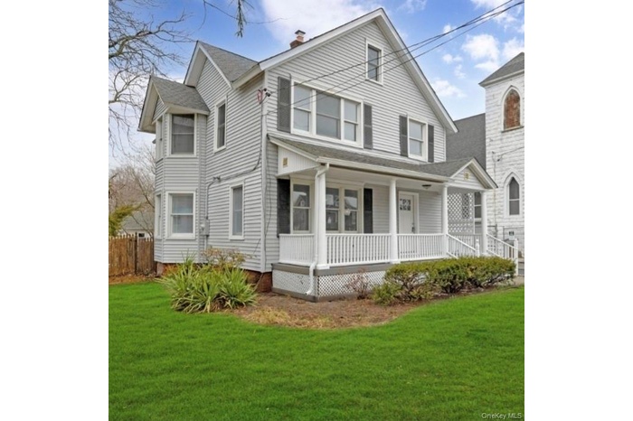 View of front of house featuring covered porch, a chimney, and roof with shingles