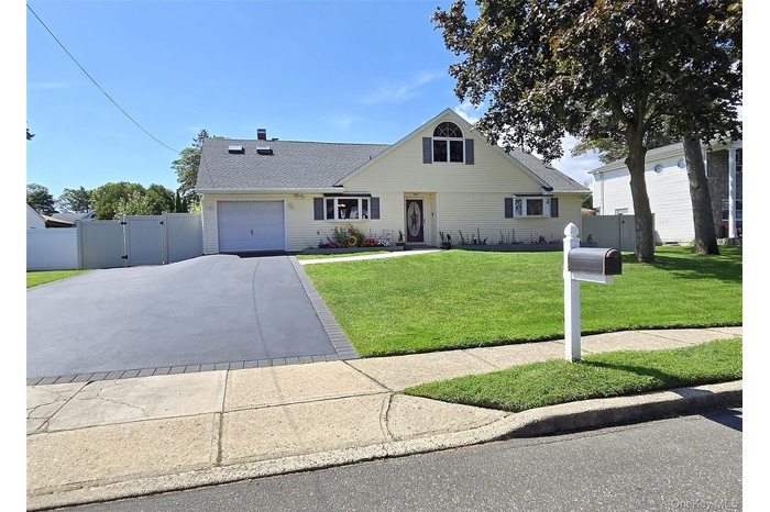 View of front of house with a gate, concrete driveway, a garage, and roof with shingles