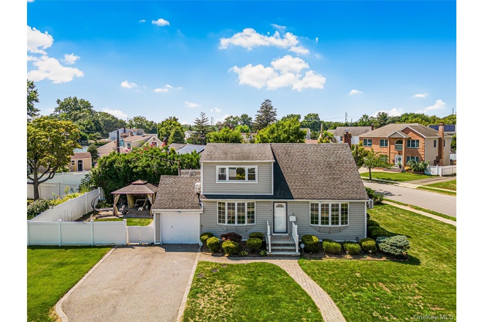 View of front of property featuring a residential view, asphalt driveway, roof with shingles, and an attached garage