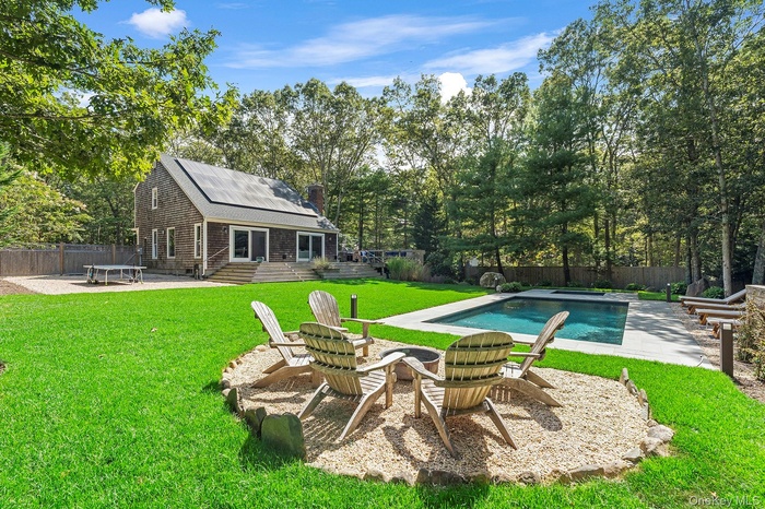 View of swimming pool featuring a patio, an outdoor fire pit, a fenced backyard, and view of wooded area