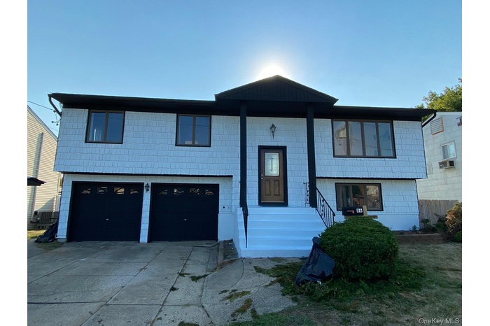 Raised ranch featuring concrete driveway and an attached garage