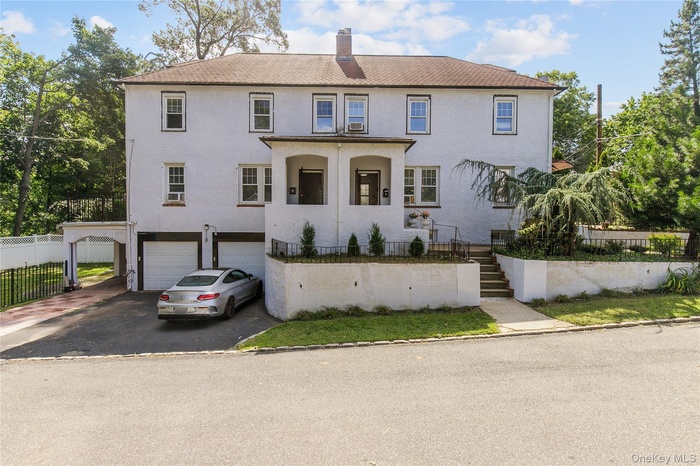 View of front of property with stairs, driveway, a garage, and a chimney