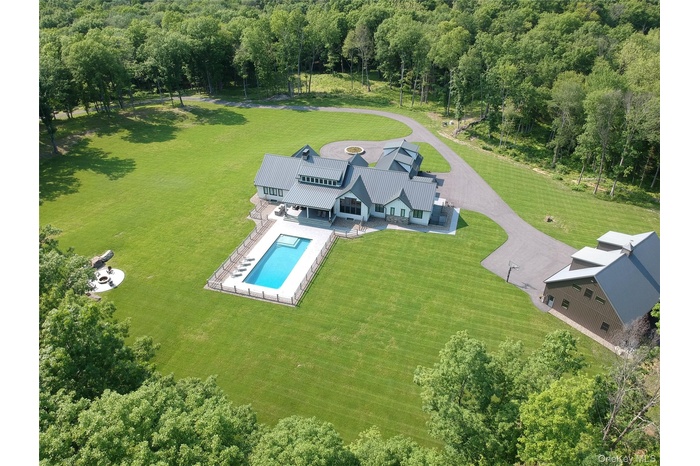Aerial view of property and surrounding area with a pool area and a forest