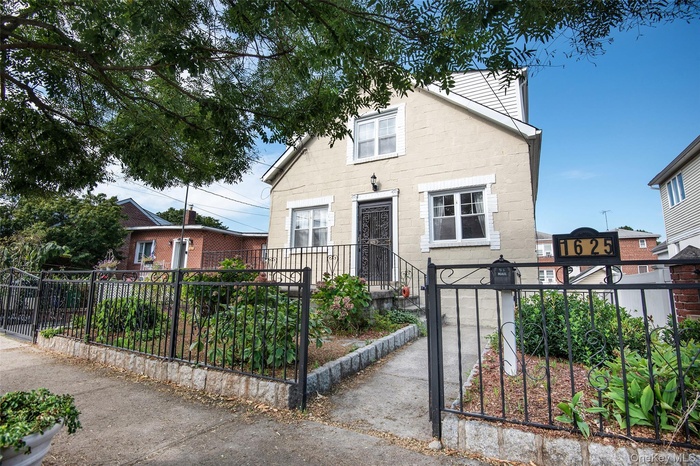 View of front facade with a fenced front yard, stone siding, and a gate