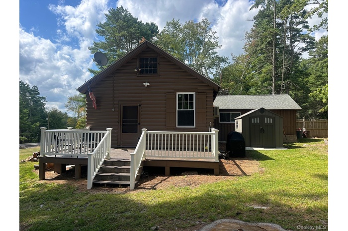 Back of house with a storage unit and a wooden deck