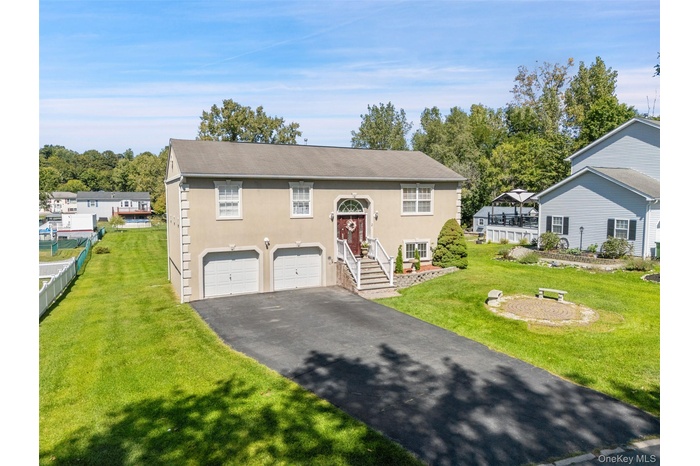 Bi-level home with asphalt driveway, stucco siding, and a garage