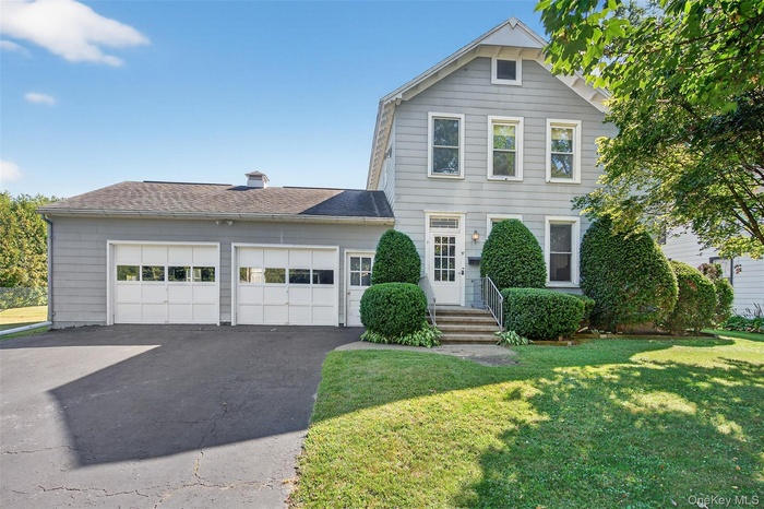 View of front of house with asphalt driveway, a shingled roof, a front lawn, and an attached garage