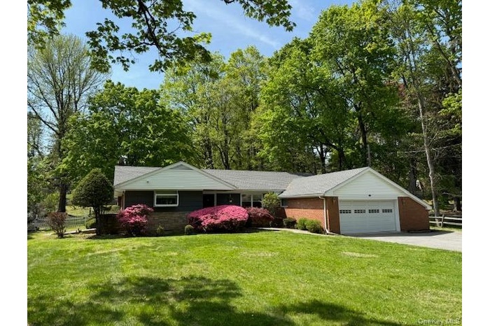 Ranch-style home with fence, an attached garage, driveway, and a front lawn
