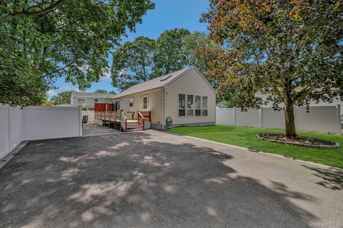 Front of property with a huge driveway and a deck