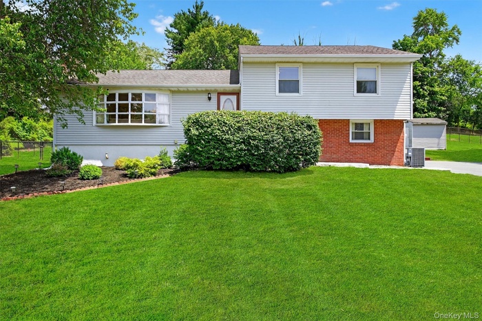 Rear view of property featuring brick siding and roof with shingles