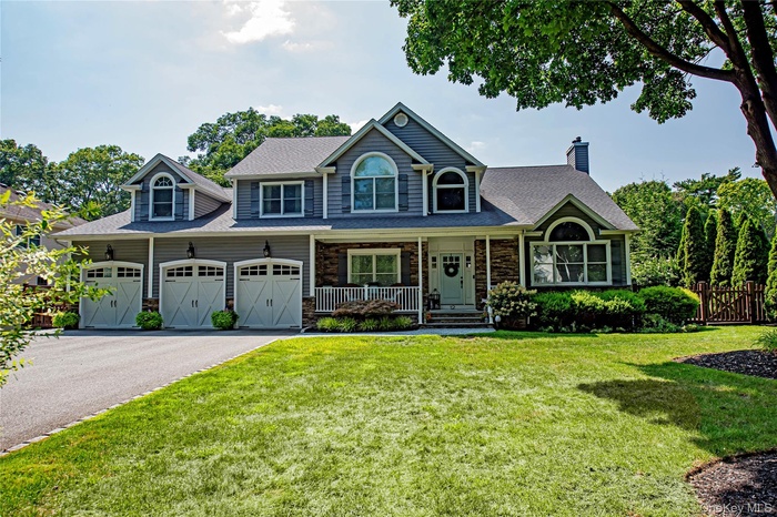 View of front with a porch, stone siding, and driveway